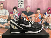 Side view of a black basketball shoe with a white side logo, white laces, textured upper, and gold number 2 detail