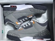 Pair of grey Air Jordan 3 sneakers with elephant-print panels and orange eyelets in a box
