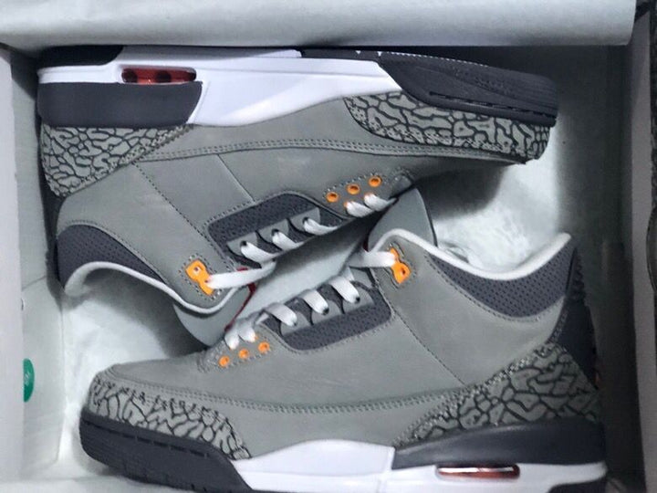 Pair of grey Air Jordan 3 sneakers with elephant-print panels and orange eyelets in a box