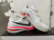 Two white Nike basketball shoes displayed together, showing textured uppers and bright accent details