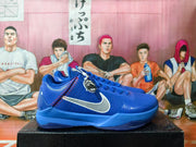 Side view of a blue Nike Kobe basketball shoe with a white Swoosh and red stitching.