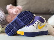 Pair of white, purple, and yellow high-top sneakers with one shoe angled to show the textured outsole tread.