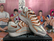 Angled view of two white, grey and orange Nike sneakers showing the layered upper and contrasting laces.