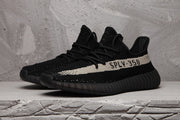 Front three-quarter view showing the black knit-style upper, laces and contrasting side stripe.