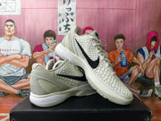 Off-white and gray Nike basketball sneakers shown from the side, with black Swoosh details and raised textured panels.
