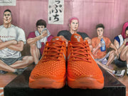 Front view of matching orange Nike basketball sneakers with textured toe boxes, orange laces, and padded tongues.