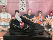 Black Nike basketball sneakers shown in profile on a shoebox, with a white Swoosh and NBA tag visible.