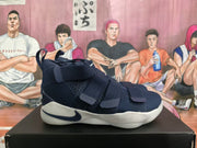Side view of a navy blue Nike basketball sneaker showing multiple straps, a side Swoosh, textured upper panels, and a sculpted light-colored sole.