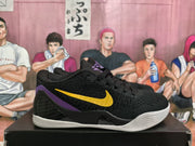 Side profile of a black Nike basketball sneaker with a yellow Swoosh, purple heel accent, textured upper, and white outsole.