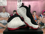 Angled view of the pair highlighting the molded sidewalls, pull tabs, black uppers, and red soles.