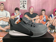 Side profile of a dark gray and black low-top basketball sneaker with a textured toe area and contrasting sole.