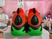 Rear view of the pair showing orange heels, black heel details, pull tabs, and bright green rubber outsoles.