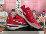 Angled view of two red Nike basketball sneakers highlighting the textured upper, white and dark blue details, heel branding, and translucent soles.