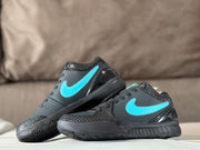 Angled view of the black and turquoise sneakers highlighting the turquoise side logos, textured panels, and dark rubber outsoles.