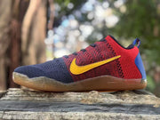 Side view of a red, navy, and blue Kobe 11 sneaker with a yellow Swoosh