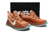 Brown and turquoise sneaker pair presented in front of a black shoebox.