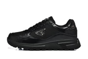 Side profile of a black low-top sneaker with layered panels and a triangular side plaque