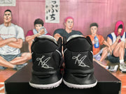 Rear view of black and white Nike basketball sneakers showing white heel embroidery, black collars, and white outsole edges.