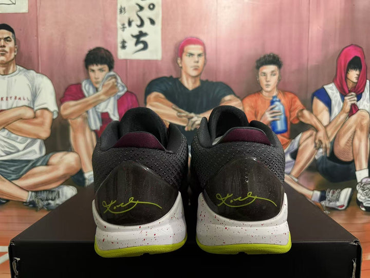 Rear view of Nike basketball sneakers showing black textured heel panels, burgundy collar details, green accents, and a speckled white midsole.