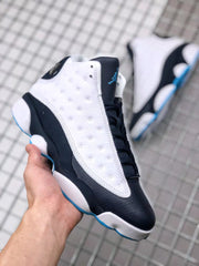 Three-quarter view showing the black toe, white perforated side panel, black laces, and blue accents.