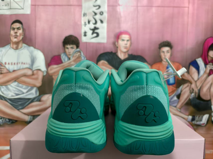 Rear view of green basketball-style sneakers showing padded collars, textured heel panels, and darker green heel accents.