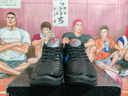 Front view of the pair showing black textured uppers, gray tongues with red logos, black laces, and blue accents.