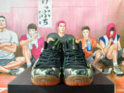 Front view of camouflage Nike basketball shoes with black laces, neon accents, and gum-colored outsoles.
