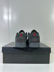 Rear view of dark grey and black low-top sneakers with red heel details on a shoebox