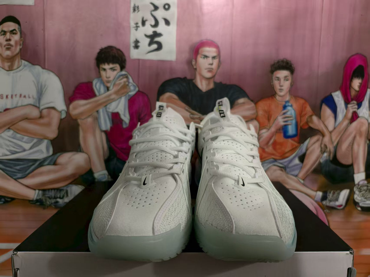 Front view of white Nike basketball sneakers with perforated uppers and black Swoosh details, positioned on a shoebox.