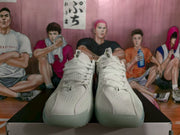 Front view of white Nike basketball sneakers with perforated uppers and black Swoosh details, positioned on a shoebox.