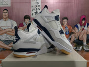 Angled view of the pair showing the white and navy upper, gum-colored outsole, and layered midsole design.