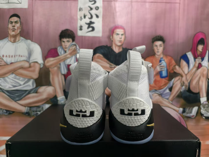 Rear view of white and black high-top basketball sneakers with gold accents, textured collars, and heel details.