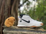 White and black Nike high-top sneaker displayed outdoors beside a small plush toy.