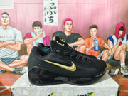 Side view of a black Nike Kobe basketball shoe with a gold-tone Swoosh and glossy black sole