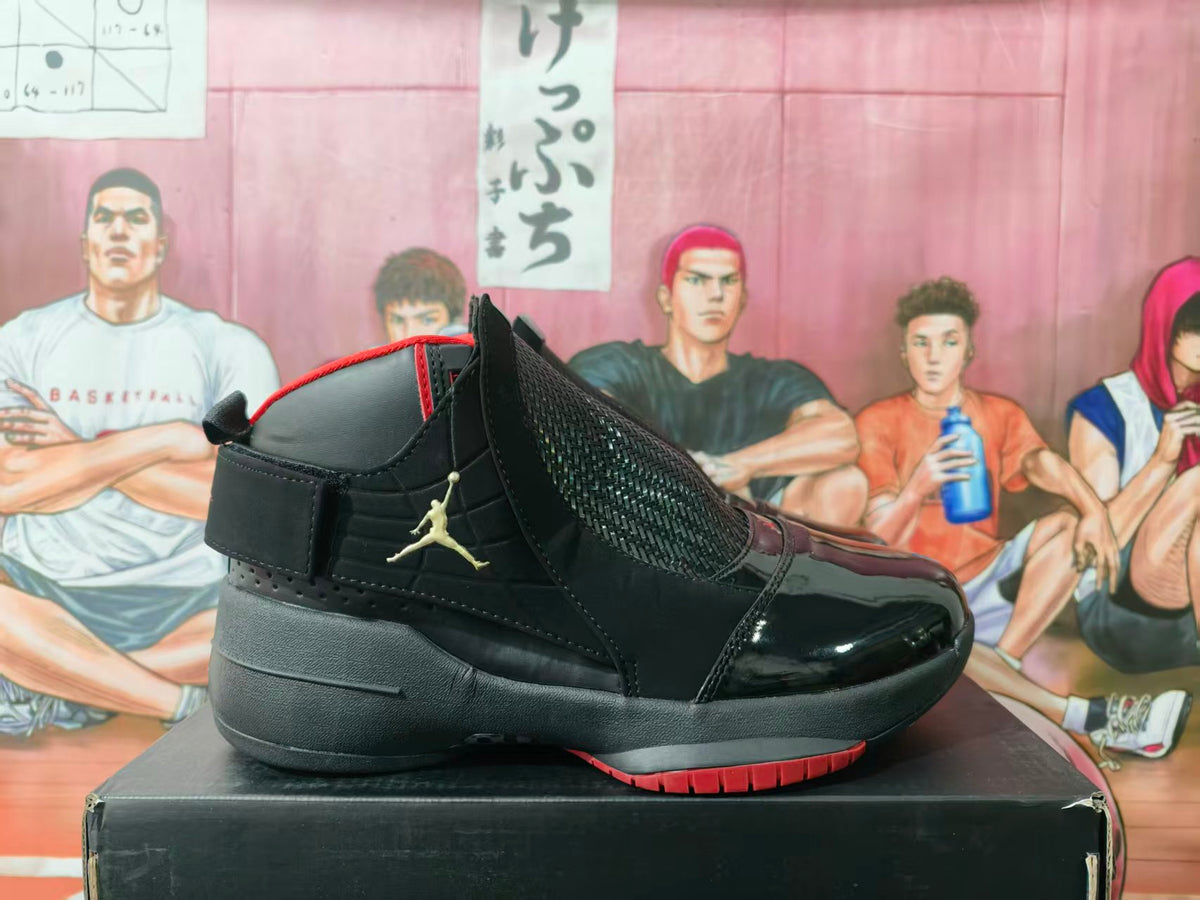 Side view of a black and red high-top basketball sneaker with a visible Jumpman logo, textured upper, ankle strap, and glossy toe section.