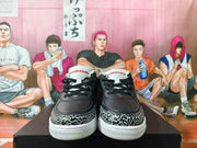 Front view of black and white low-top sneakers with elephant-print toe panels and red tongue details.