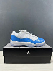 Side profile of a white and university blue low-top sneaker displayed on a black shoe box.