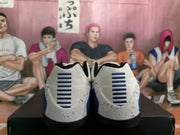 Rear view of white and blue Nike basketball sneakers showing blue heel detailing, black collars and speckled heel panels.