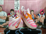 Angled view displaying the white and pink Nike sneakers, orange laces, contrasting Swoosh, and translucent outsole.