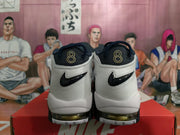 Rear view of white and dark navy Nike basketball shoes with gold-outlined number 8 heel embroidery.
