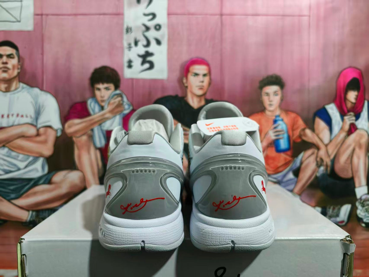 Rear view of white and gray Nike basketball sneakers with red heel accents and gray midsoles, displayed on a shoebox.