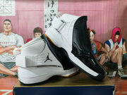 Side view showing the white high-top sneaker, black textured panels, wide ankle strap, and contrasting gum outsole.