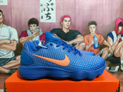 Side view of a blue Nike sneaker with an orange Swoosh and textured upper.