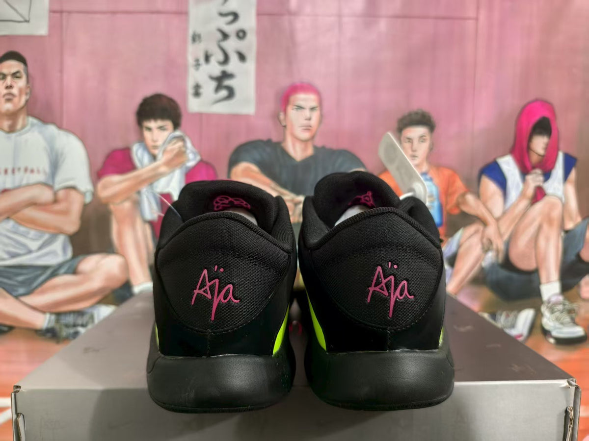 Rear view of black Nike basketball sneakers with pink Ja heel markings and green side accents on a shoebox.