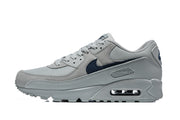 Side view of a grey and navy Nike Air Max 90 sneaker showing the Swoosh and visible heel Air unit.