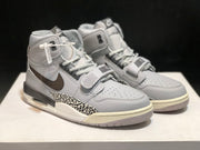 Three-quarter front view of the pair showing the grey and white color scheme, brown Swooshes and elephant-print panels.