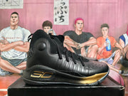 Side profile showing the black upper, gold-colored midsole accent, and speckled sole.