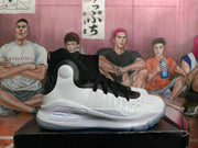 Side view of a white and black high-top basketball shoe with a perforated toe and lace-up closure.