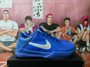 Side profile of a blue Nike basketball sneaker showing the white Swoosh, textured upper, and layered sole.