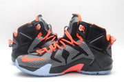 Front three-quarter view of matching black, grey and orange high-top basketball sneakers with translucent outsoles.